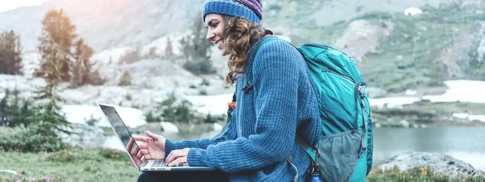 Female traveler working remotely with her laptop outdoors